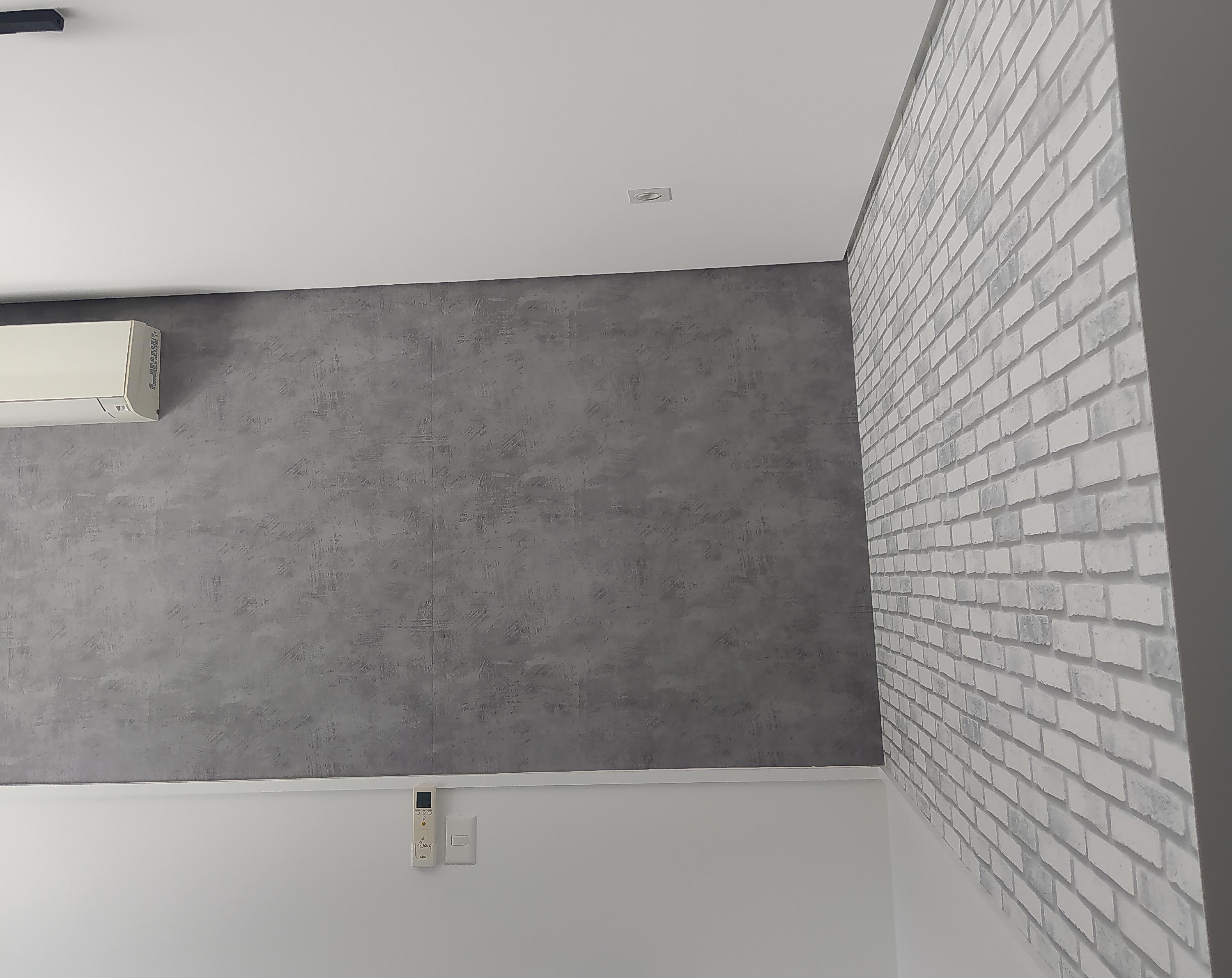 Quarto com papel de parede autoadesivo nos tons cimento queimado e tijolinho à vista